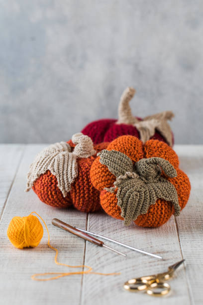 istock Knitted pumpkins with leaves crochets and scissors on table 1334676196