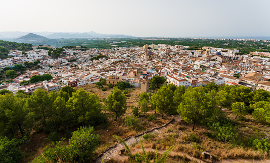 Panorama view from the castle 'Santa Anna' on the Spanish old town with the church tower and blue tiled domes of 'San Roque' in the center, Oliva, Spain