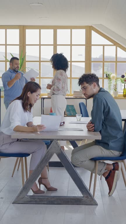 Manager discussing business with colleague in modern open plan workplace
