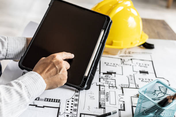 istock Architects are looking at blueprints designed on tablets, designing the house according to the homeowner's needs and building standards. Architects concept design houses according to requirements. 1334682977