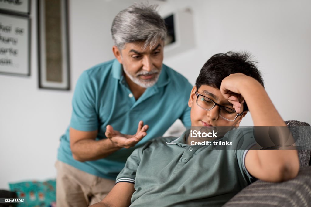 Frustrated father scolding his son Frustrated father scolding his teenage son at home Parent Stock Photo