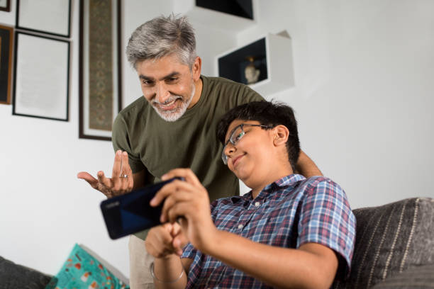 istock Father and son using mobile phone at home 1334683788