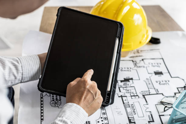 istock Architects are looking at blueprints designed on tablets, designing the house according to the homeowner's needs and building standards. Architects concept design houses according to requirements. 1334683990