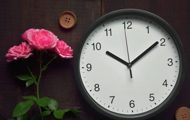 istock classic clock and rose on wooden background 1334684358