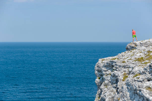 gotland sverige july  9 - 2014  - unknown young man looking out over the sea from a cliff on the Swedish island of Gotland which is quite close to Stockholm city by the Baltic Sea,