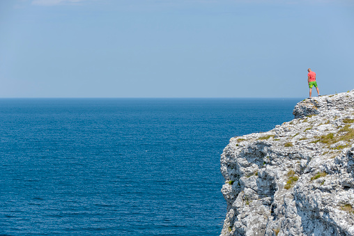 gotland sverige july  9 - 2014  - unknown young man looking out over the sea from a cliff on the Swedish island of Gotland which is quite close to Stockholm city by the Baltic Sea,