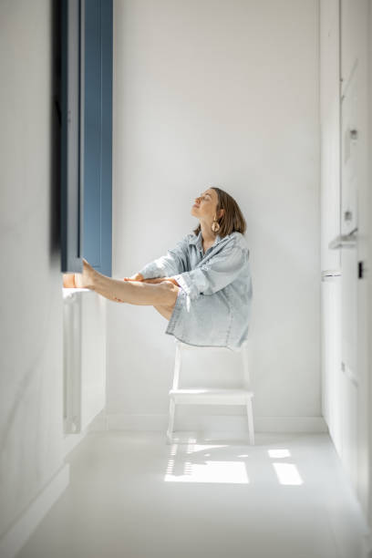 istock Woman sitting alone by the window at home 1334694369
