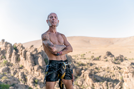 Athletic mature man portrait before climbing on overhanging cliff rock