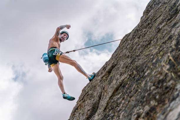 Athletic old man climbing on overhanging cliff rock