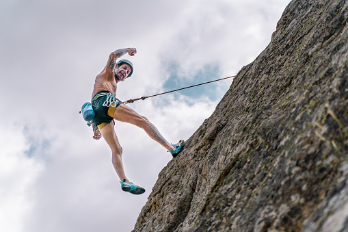 Athletic old man climbing on overhanging cliff rock