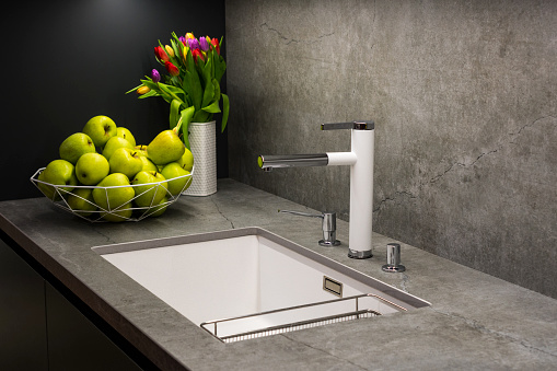 Close-up of faucet and sink in the modern luxury kitchen. Modern kitchen house interior.