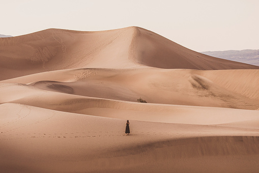 Woman holding camera in vast wide open desert sand dunes