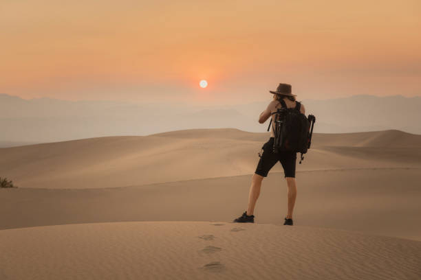 istock Man photographing sunset in desert sand dunes 1334699759