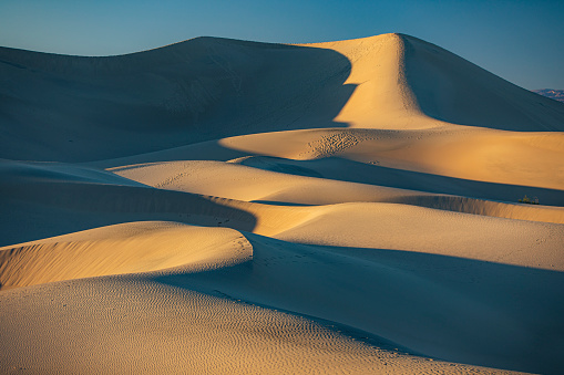 Sun setting across desert sand dunes