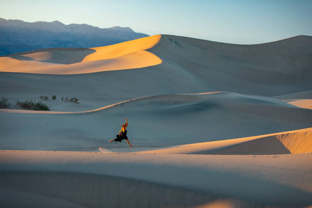 istock Woman leaping through desert dunes at sunset 1334700573