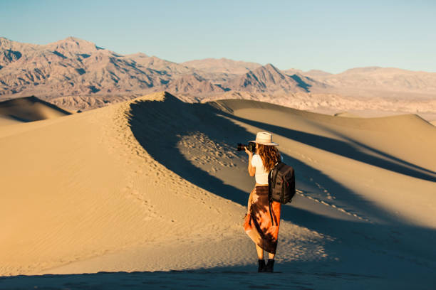 istock Woman taking photo  while walking through desert sand dunes 1334700983