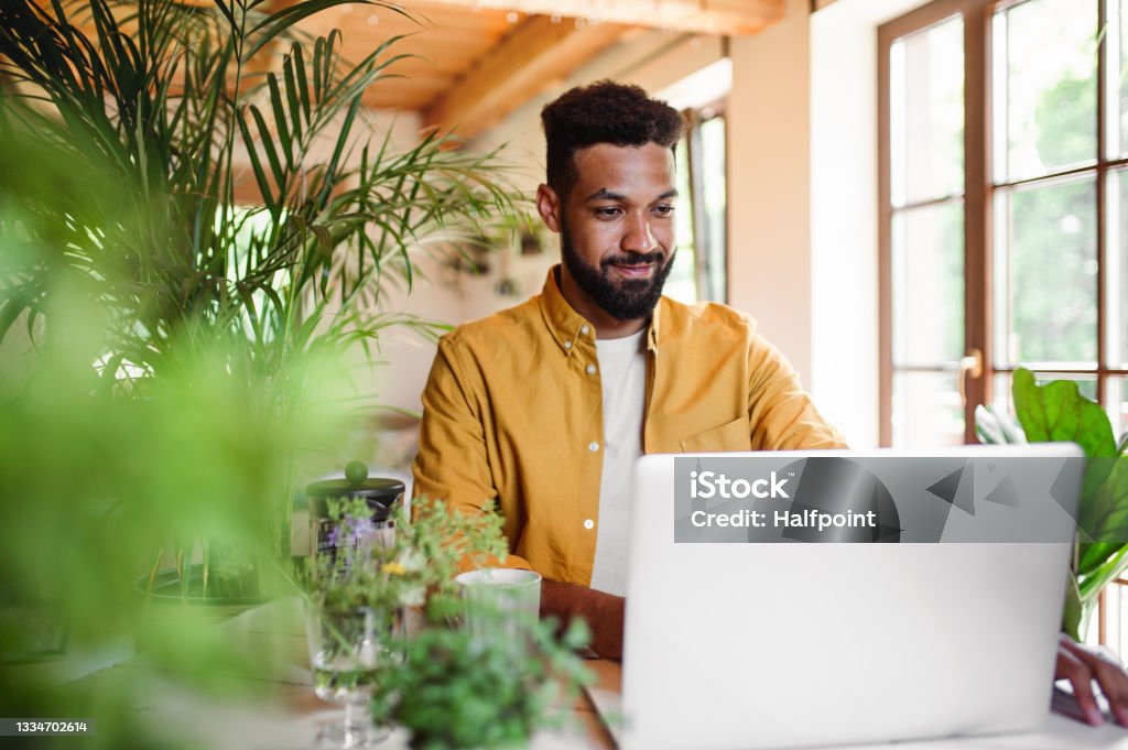 Young man with laptop and coffee working indoors, home office concept. A young man with laptop and coffee working indoors, home office concept. Laptop Stock Photo