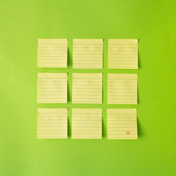 istock Yellow post-it notes arranged in square of nine , with one note with red smile wright on it. Blue background. minimal creative concept, 1334702907