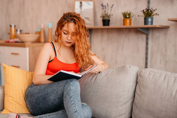 istock Woman At Home sitting on sofa and reading book 1334706338