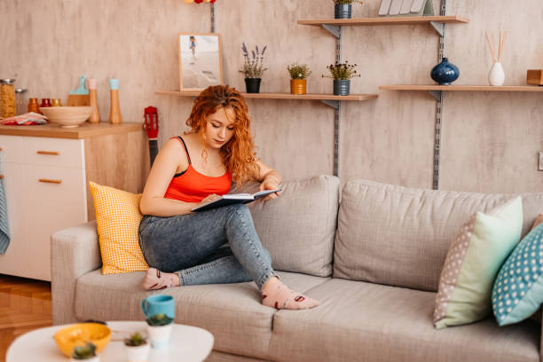 istock Woman At Home sitting on sofa and reading book 1334706379