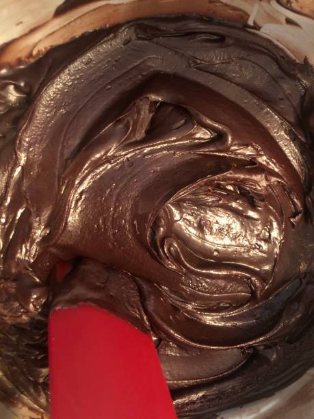 primo colpo in testa guardando in basso sulla pastella torta al cioccolato in una ciotola con una spatola rossa - cake batter foto e immagini stock