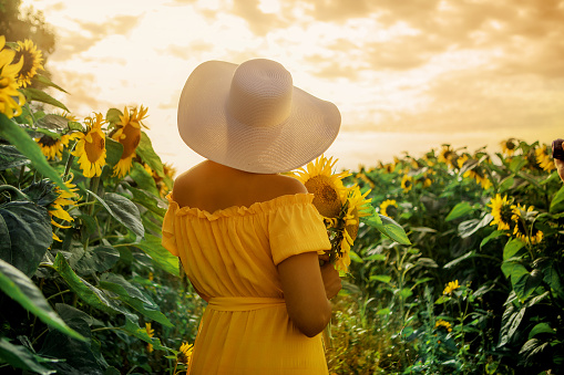 A beautiful mixed race woman enjoying some free time in a colourful field of sunflowers on a lovely summer's day