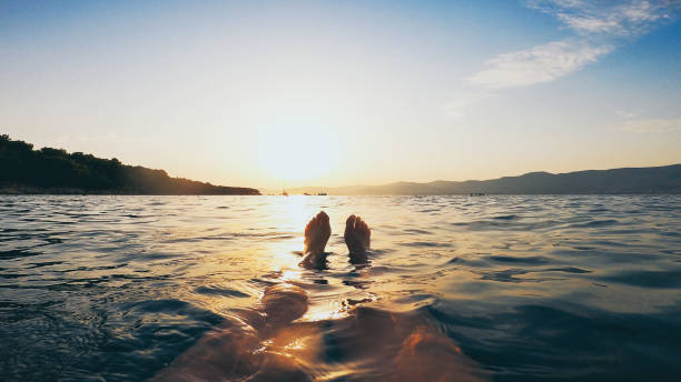 point de vue personnel des jambes de femme, nager dans la mer adriatique au coucher du soleil, split, croatie - leg split photos et images de collection