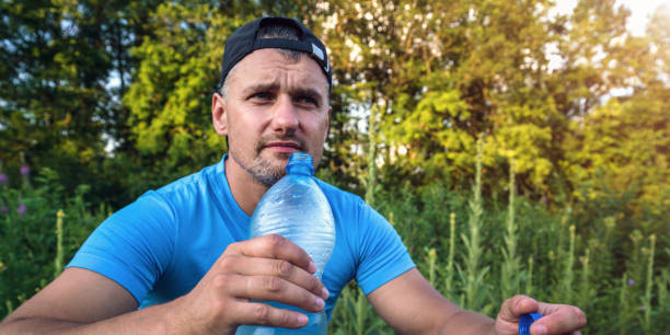 istock man in cap and blue shirt sits and drinks water from bottle 1334729638