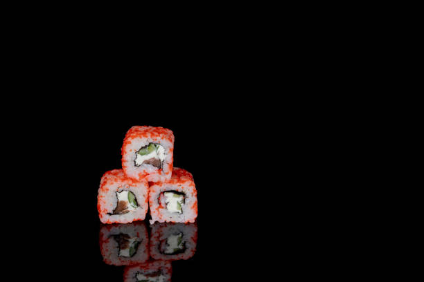 istock Philadelphia roll with salmon, cheese and cucumber on a black background with reflection. Sushi Philadelphia 1334730294