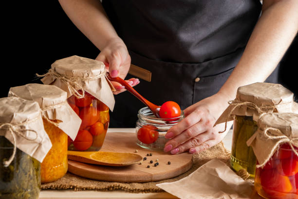 istock Woman cans and pickles vegetables. Fermentation process of tomatoes. Healthy eco food. 1334734024