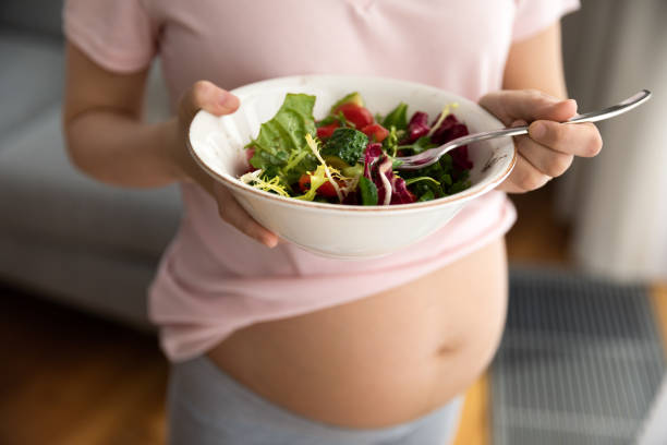 istock Expectant mother holding bowl with fresh vegetable salad 1334740048