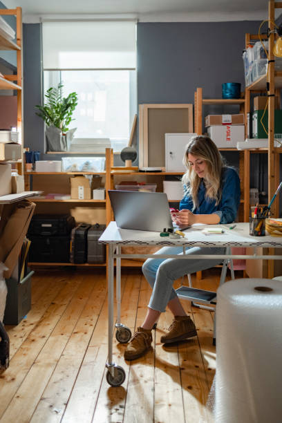 istock Happy Female Entrepreneur Working on Her Laptop at Her Storage Facility ( Vertical) 1334742483