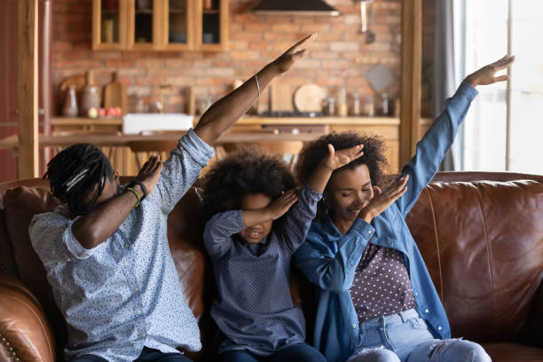 Smiling biracial parents with daughter dab dance Happy young African American family with small teen daughter dance together do popular viral dab gesture. Overjoyed biracial parents with little teenage ethnic girl child have fun relax at home. dab dance stock pictures, royalty-free photos & images
