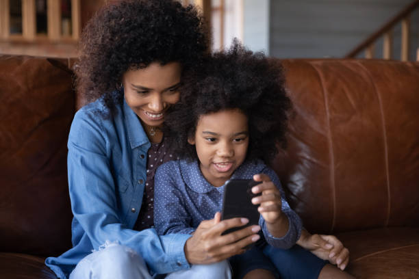 istock Happy biracial mom and daughter talk on cellphone call 1334745222