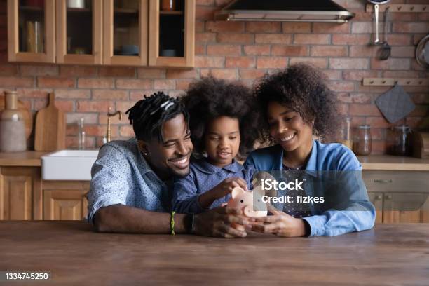 Happy ethnic family with kid save money in piggybank