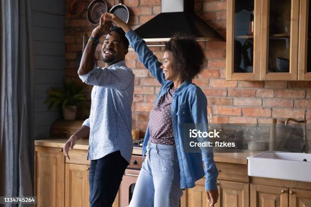 Happy Biracial Couple Dance In Cozy Home Kitchen Stock Photo - Download Image Now - Couple - Relationship, Two Parents, Dancing