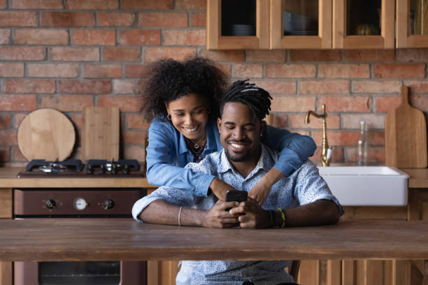 Smiling young biracial couple use cellphone together