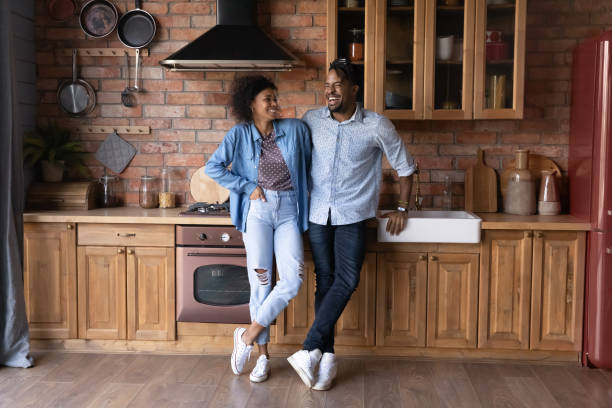 Excited ethnic couple have fun relax at home kitchen