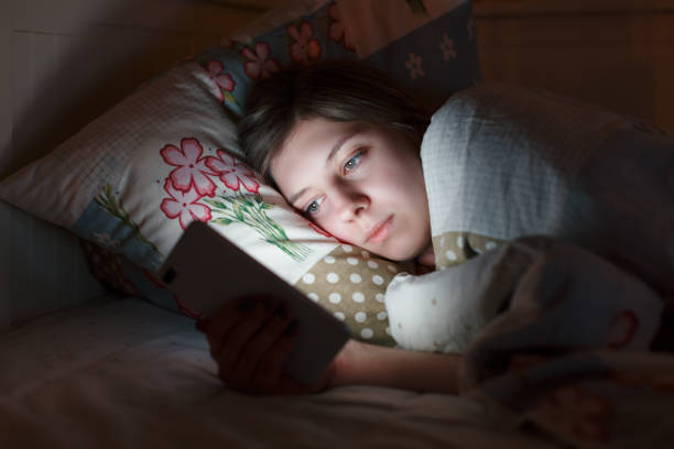 istock Young sleepy tired girl lying in bed using smartphone at late night 1334745973