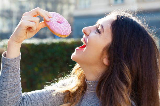 istock Young woman eating a donut 1334747541