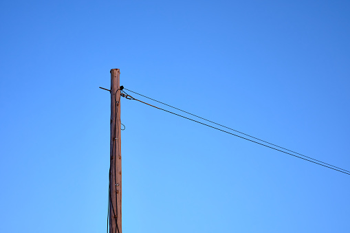 detail of a wooden communication pole with a blue sky in the background