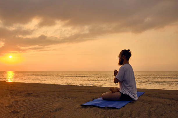 istock Portrait of man meditating at beach 1334749359