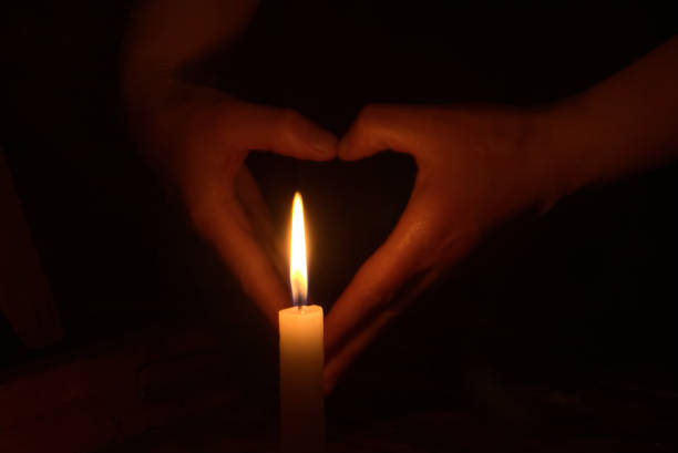 istock Lighted candles in love gesture with black background 1334755007