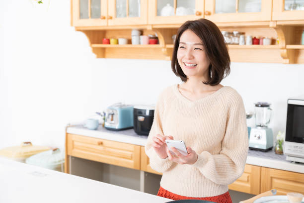istock attractive asian woman to see a smart phone,kitchen 1334762680
