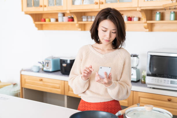 istock attractive asian woman to see a smart phone,kitchen 1334763063