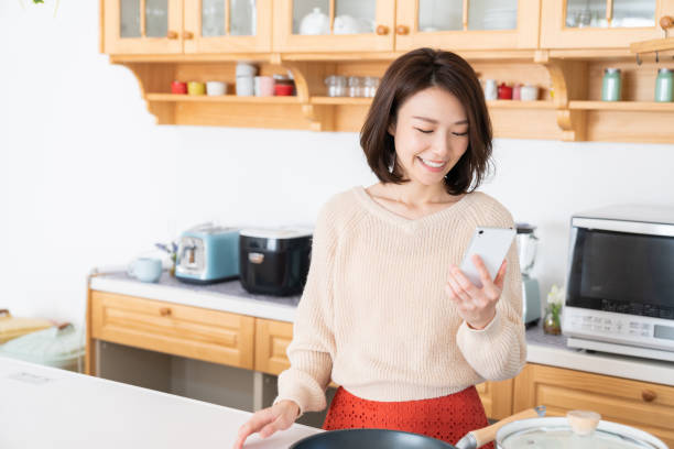 attractive asian woman to see a smart phone,kitchen