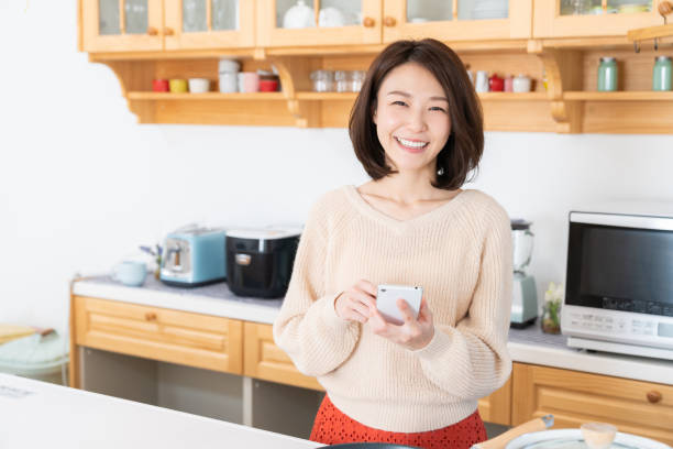 istock attractive asian woman to see a smart phone,kitchen 1334763278