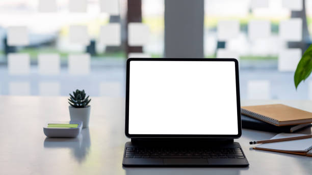istock Blank white screen of a laptop and a notebook placed on the table at the office. Mock up. 1334764314
