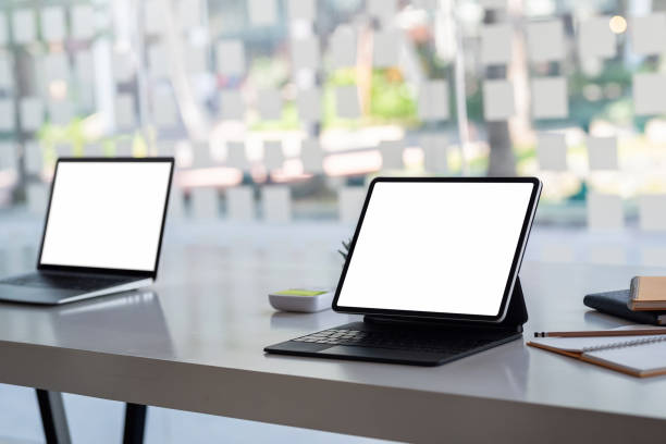 istock Blank white screen of a laptop and a notebook placed on the table at the office. Mock up. 1334764321