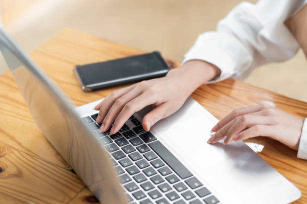 istock Close up. Woman sitting at desk and working at laptop computer. 1334764936